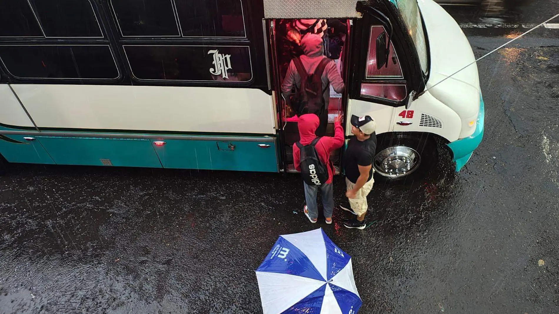 Personas subiendo al camión mientras llueve